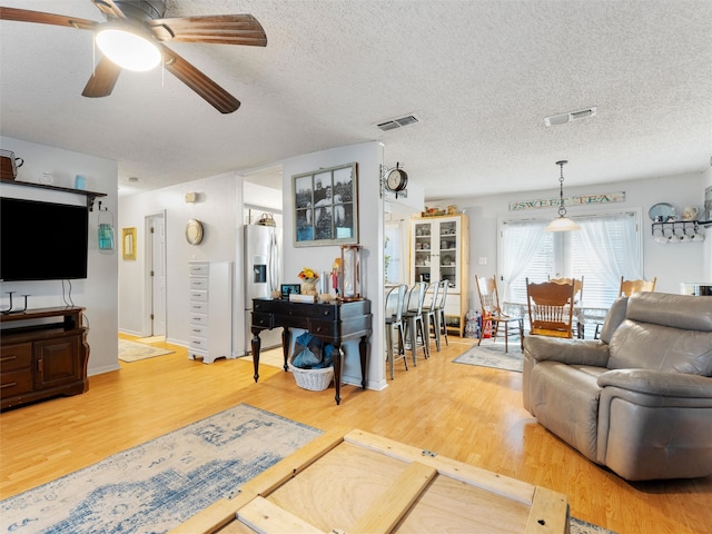 living room featuring hardwood / wood-style floors, a textured ceiling, and ceiling fan