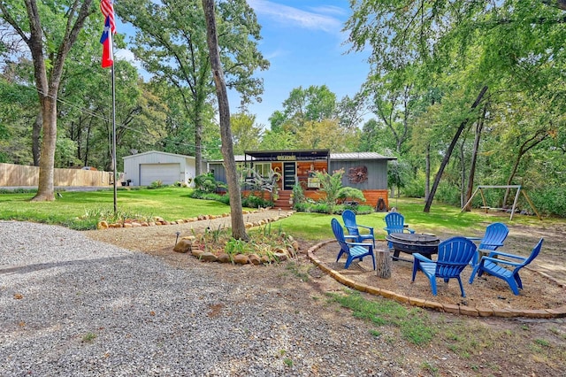 view of yard with an outdoor fire pit, a detached garage, an outbuilding, and fence