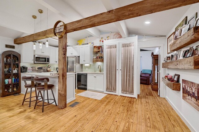 kitchen featuring white cabinets, hanging light fixtures, appliances with stainless steel finishes, light countertops, and open shelves