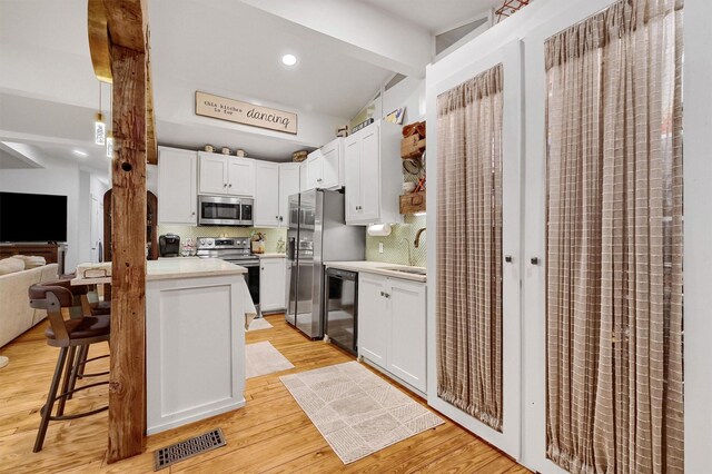 kitchen with appliances with stainless steel finishes, light countertops, open floor plan, and white cabinetry