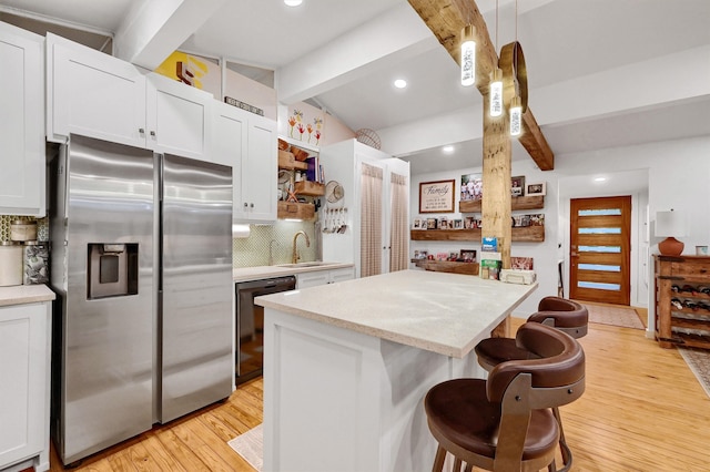 kitchen featuring a kitchen island, white cabinets, black dishwasher, stainless steel fridge, and decorative light fixtures