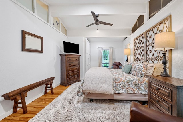 bedroom with ceiling fan, beam ceiling, and light hardwood / wood-style flooring