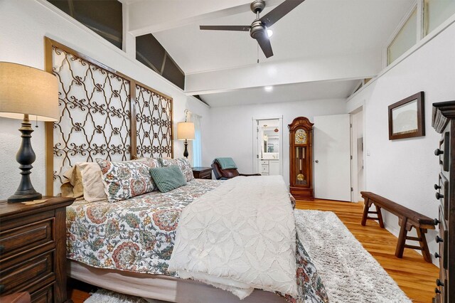 bedroom featuring vaulted ceiling with beams, light wood finished floors, a ceiling fan, and connected bathroom