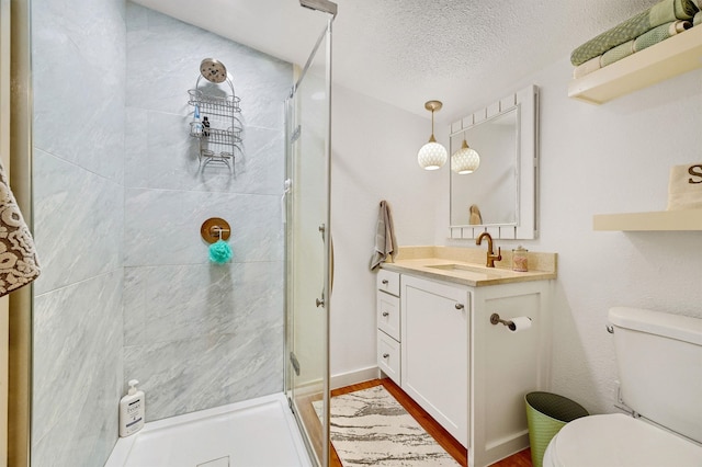 bathroom with a textured ceiling, hardwood / wood-style floors, vanity, an enclosed shower, and toilet