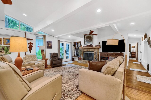 living room featuring a stone fireplace, hardwood / wood-style floors, vaulted ceiling with beams, and ceiling fan