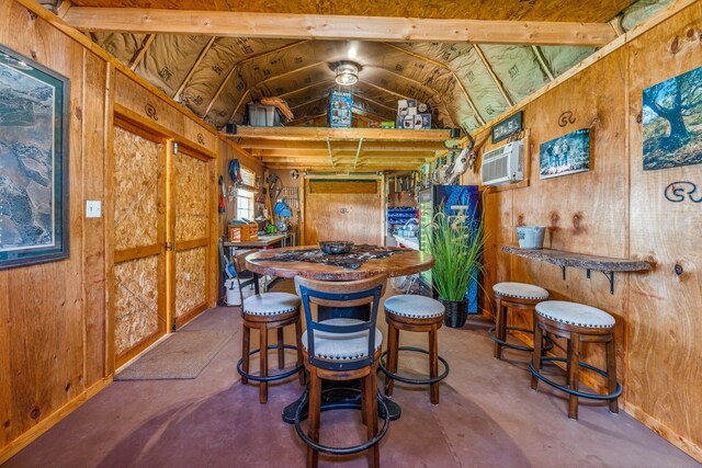 dining space featuring a wall mounted AC, lofted ceiling with beams, and wooden walls