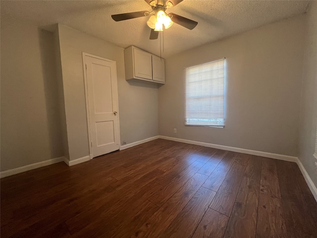 empty room with dark wood-type flooring, a textured ceiling, and ceiling fan