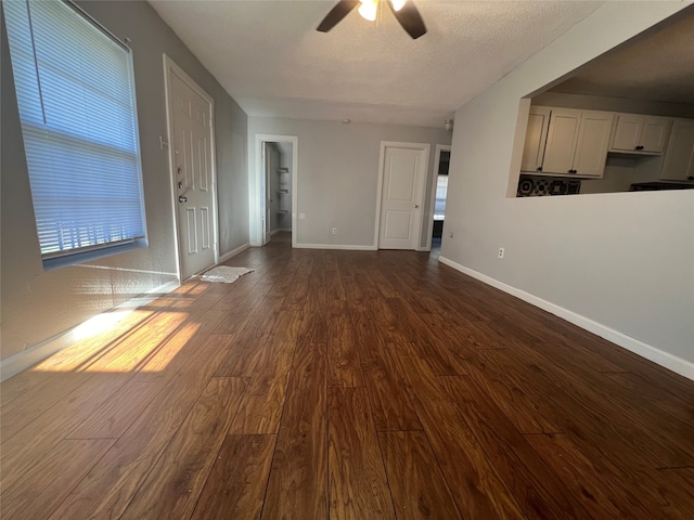 unfurnished living room with dark hardwood / wood-style flooring, a textured ceiling, and ceiling fan