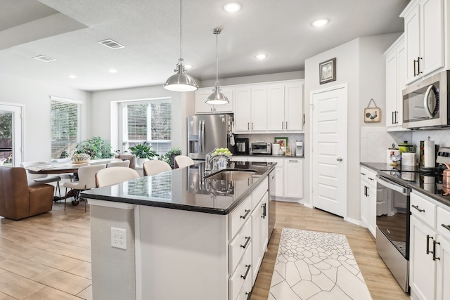 kitchen with sink, white cabinetry, a kitchen island with sink, and stainless steel appliances