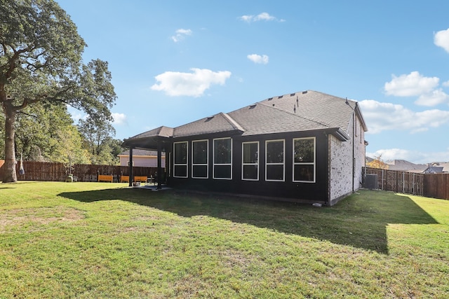 rear view of house with central air condition unit and a yard