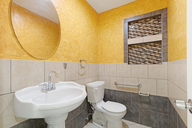 bathroom with sink, toilet, and tile walls