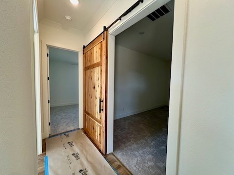 hallway with light carpet and a barn door