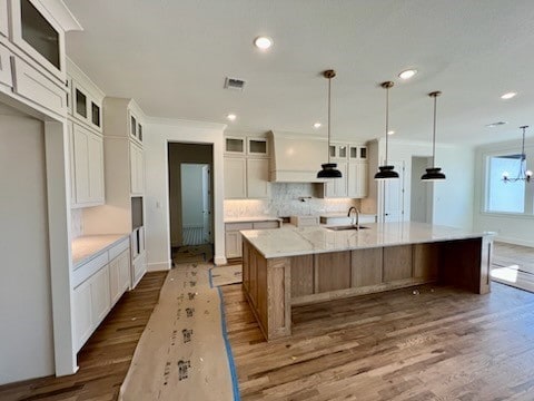 kitchen with white cabinetry, hanging light fixtures, a spacious island, and sink