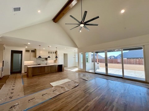 unfurnished living room featuring ceiling fan, beamed ceiling, high vaulted ceiling, and hardwood / wood-style flooring