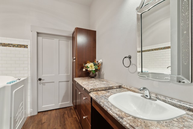 bathroom with hardwood / wood-style floors, vanity, and a tub