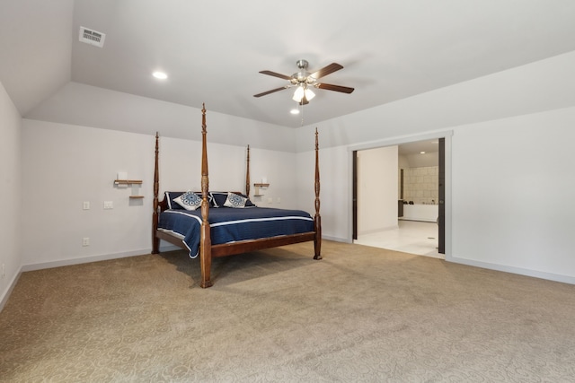 bedroom with ceiling fan, light colored carpet, ensuite bathroom, and vaulted ceiling