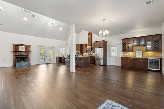 unfurnished living room with high vaulted ceiling, dark hardwood / wood-style floors, wine cooler, and a notable chandelier