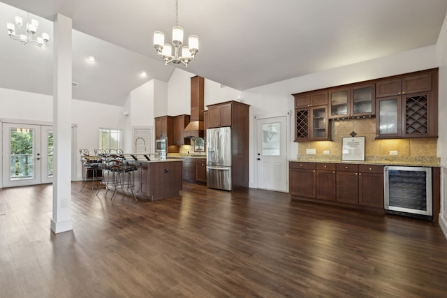 kitchen with hanging light fixtures, decorative backsplash, stainless steel fridge, a notable chandelier, and beverage cooler