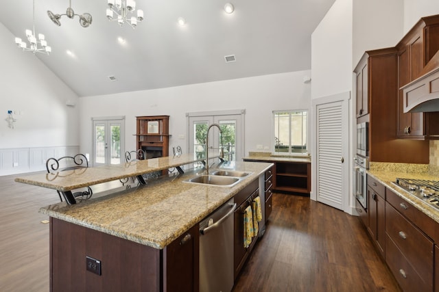 kitchen with sink, an inviting chandelier, pendant lighting, a center island with sink, and appliances with stainless steel finishes