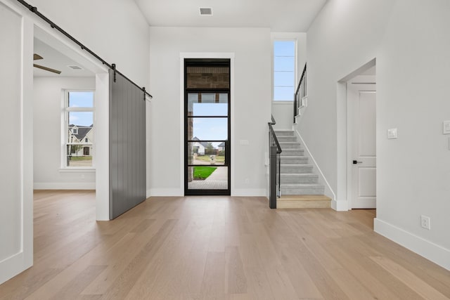 foyer featuring ceiling fan, a barn door, and light hardwood / wood-style floors