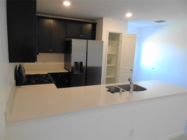 kitchen featuring kitchen peninsula, sink, stainless steel fridge, and black range oven