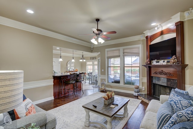 living room featuring dark hardwood / wood-style floors, ceiling fan, and ornamental molding