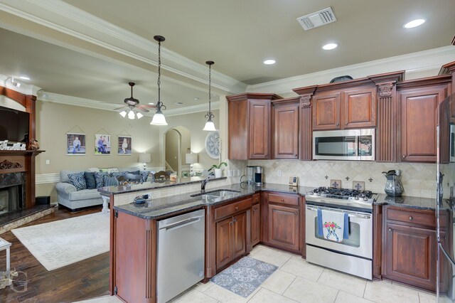 kitchen with crown molding, pendant lighting, a high end fireplace, and stainless steel appliances