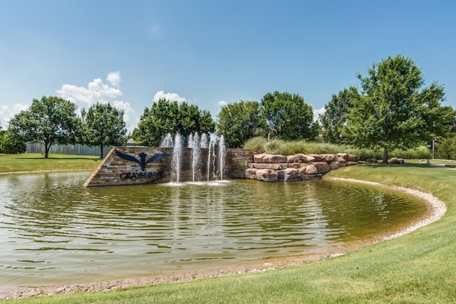 view of property's community featuring a lawn and a water view