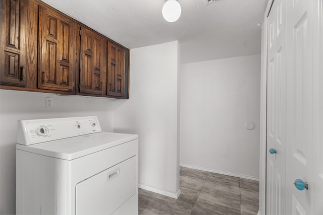 laundry room with a textured ceiling, cabinets, and washer / dryer