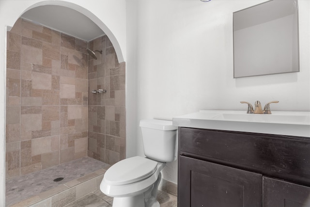 bathroom with toilet, vanity, tile patterned flooring, and a tile shower