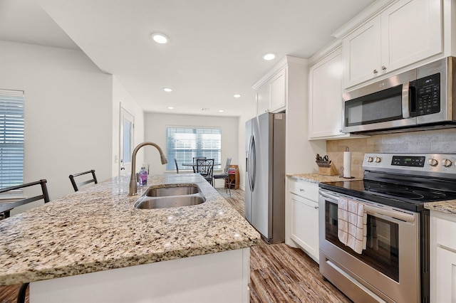 kitchen featuring a kitchen island with sink, light hardwood / wood-style flooring, white cabinets, and appliances with stainless steel finishes