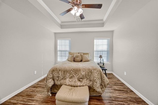 bedroom with dark wood-type flooring, a raised ceiling, ceiling fan, and crown molding