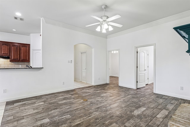 unfurnished living room featuring hardwood / wood-style floors, ceiling fan, and crown molding