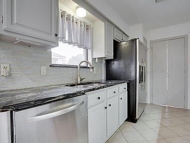 kitchen with white cabinetry, appliances with stainless steel finishes, dark stone counters, and sink