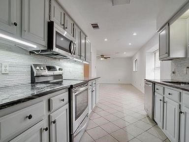 kitchen featuring stainless steel appliances, sink, ceiling fan, light tile patterned floors, and gray cabinetry