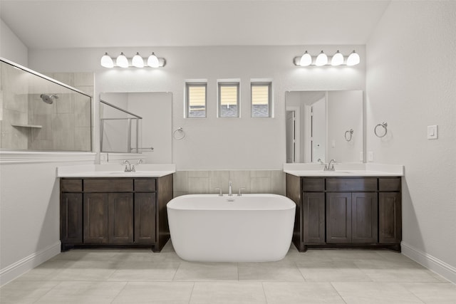 bathroom featuring a soaking tub, a shower stall, two vanities, and a sink