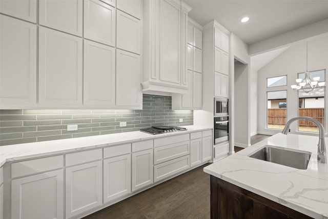 kitchen with pendant lighting, decorative backsplash, appliances with stainless steel finishes, white cabinetry, and a sink