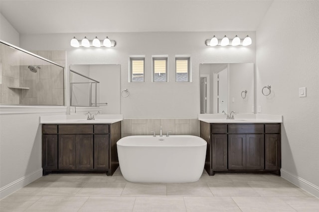 full bath featuring a stall shower, a soaking tub, two vanities, and a sink