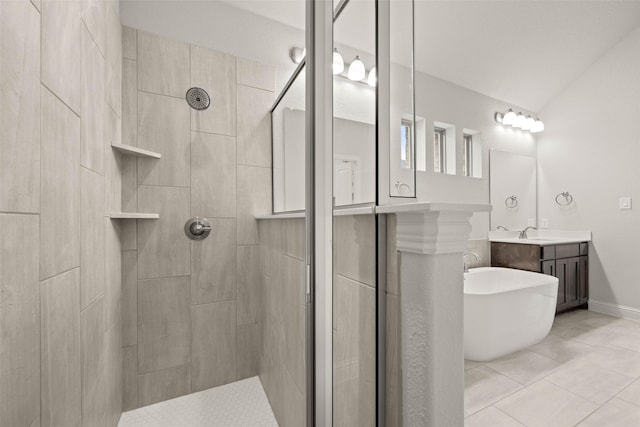 bathroom with a freestanding tub, tile patterned flooring, tiled shower, and vanity