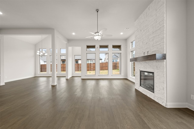 unfurnished living room with dark wood-style floors, recessed lighting, a stone fireplace, baseboards, and ceiling fan with notable chandelier