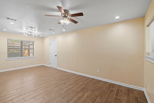 empty room featuring wood finished floors, visible vents, and baseboards