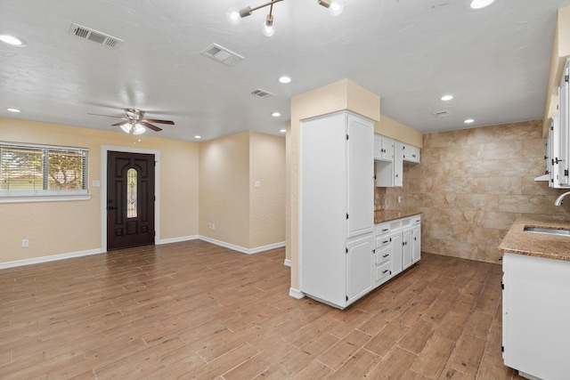 kitchen with white cabinetry, sink, and light hardwood / wood-style flooring