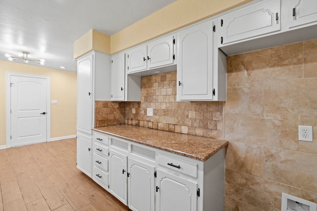 kitchen with backsplash, stone countertops, white cabinetry, and light hardwood / wood-style flooring