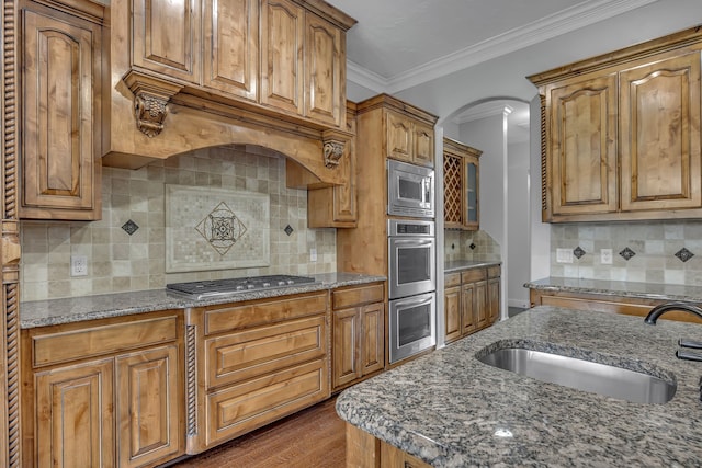 kitchen featuring stainless steel appliances, dark stone counters, backsplash, hardwood / wood-style floors, and sink