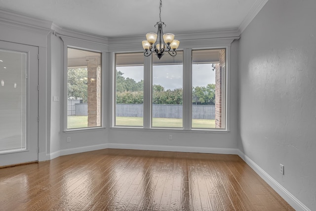 unfurnished dining area featuring wood-type flooring, a notable chandelier, and crown molding