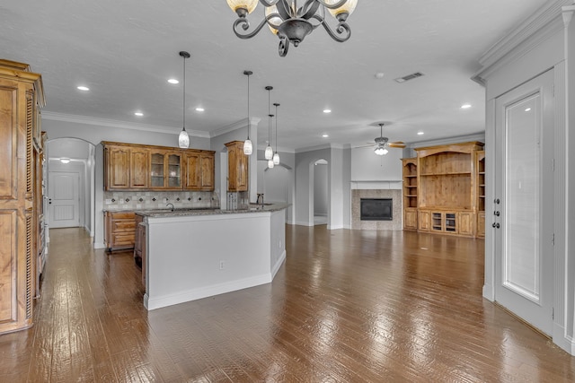 kitchen featuring tasteful backsplash, crown molding, hanging light fixtures, dark wood-type flooring, and ceiling fan with notable chandelier