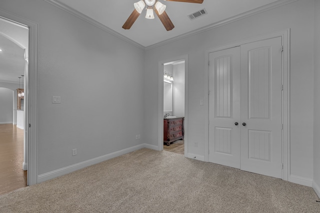 unfurnished bedroom with ensuite bathroom, ceiling fan, crown molding, light colored carpet, and a closet