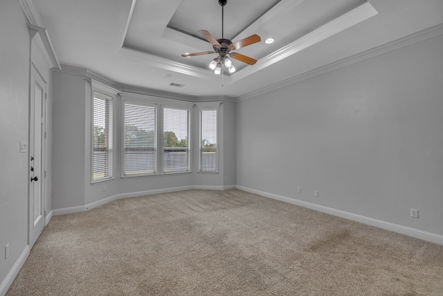 carpeted empty room featuring crown molding, ceiling fan, and a raised ceiling