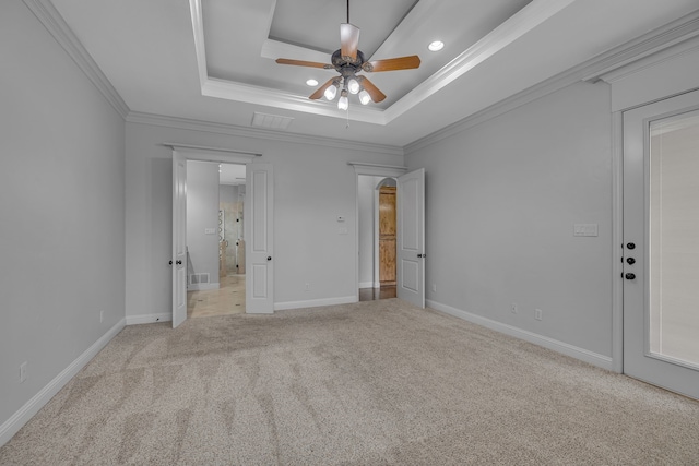 unfurnished bedroom featuring ceiling fan, a tray ceiling, light colored carpet, and ornamental molding