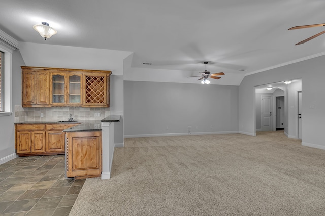 kitchen featuring vaulted ceiling, ceiling fan, dark colored carpet, and decorative backsplash